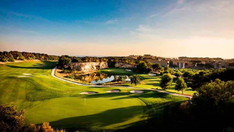 Golfbana i Salou med grön fairway, bunkrar, vattenhinder och utsikt över kusten i soligt landskap.